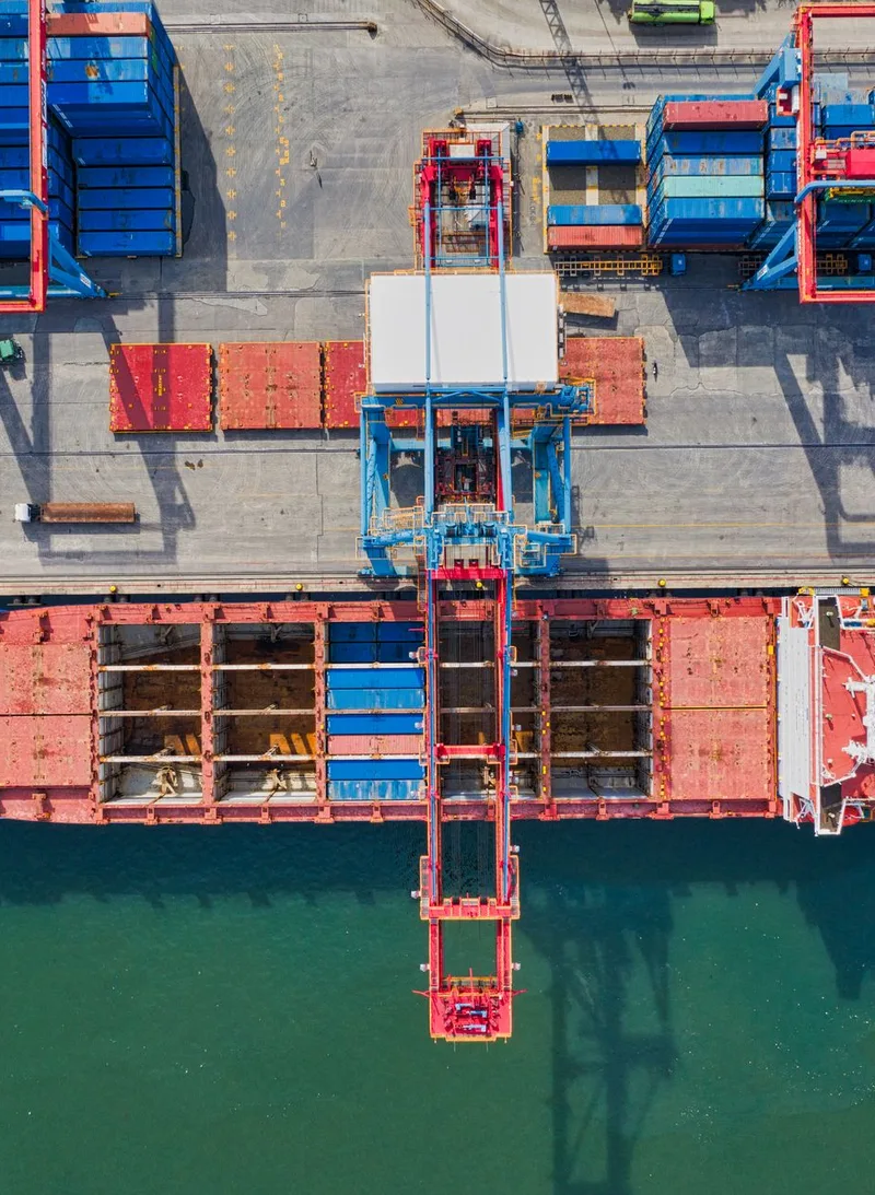 Container ship berthed beside stacked containers